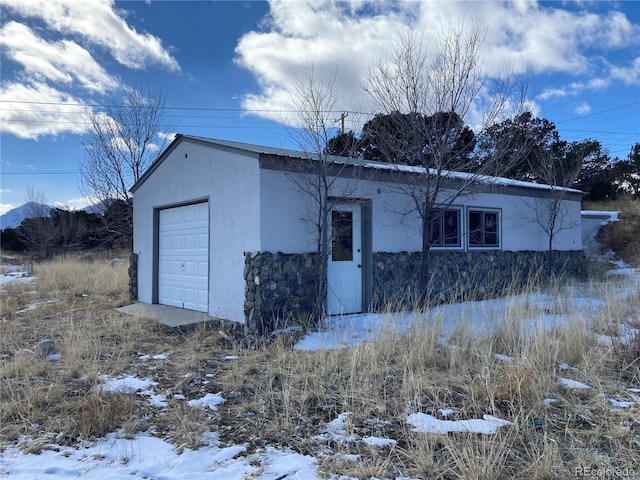 snow covered garage featuring a detached garage