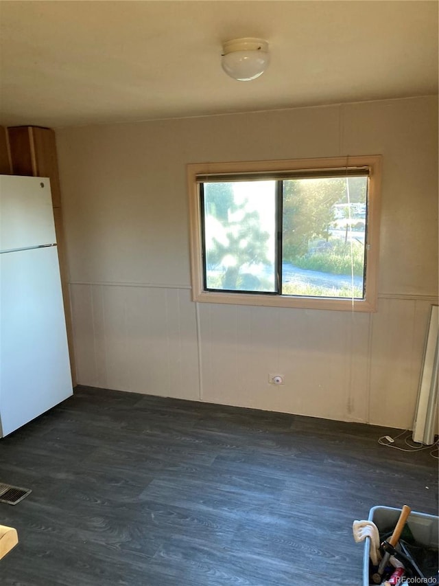 empty room featuring dark wood-type flooring, wainscoting, and visible vents