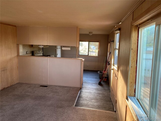 kitchen with dark colored carpet, a peninsula, visible vents, and white electric range