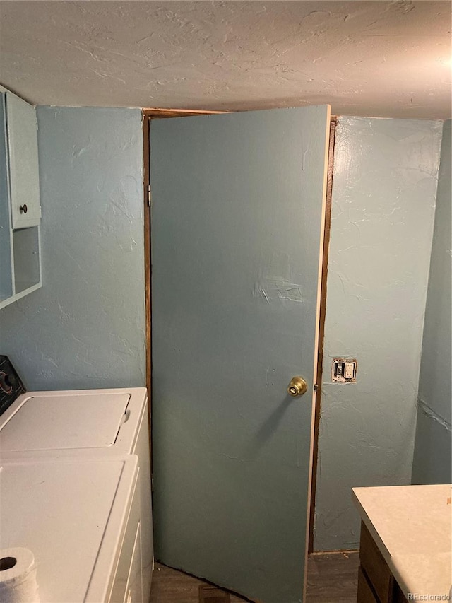 laundry area with a textured wall, laundry area, dark wood-style flooring, and washer / dryer