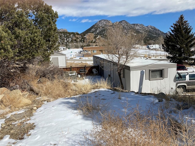 exterior space featuring fence, a mountain view, and an outbuilding