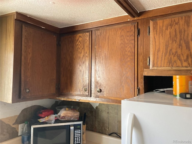 clothes washing area with cabinet space and a textured ceiling