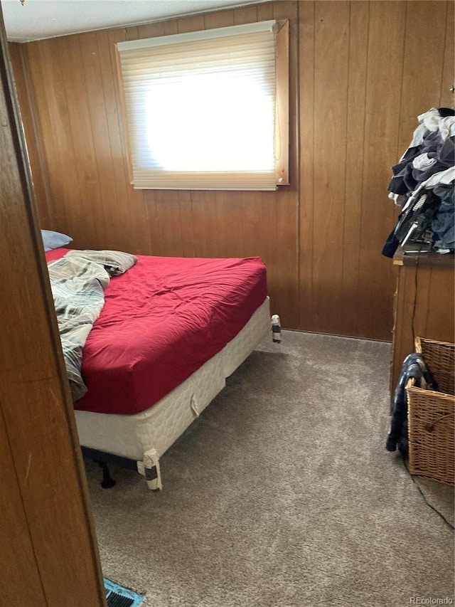 carpeted bedroom featuring wood walls