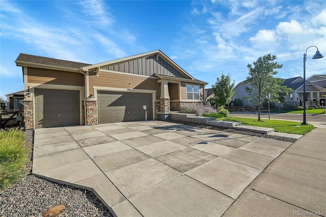 craftsman house featuring a garage, stone siding, driveway, and board and batten siding