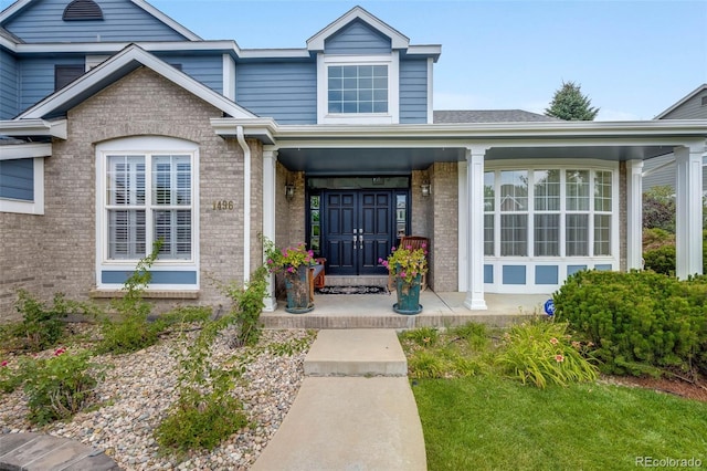 entrance to property featuring brick siding and covered porch