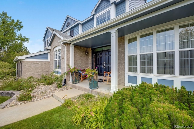 doorway to property with brick siding and covered porch