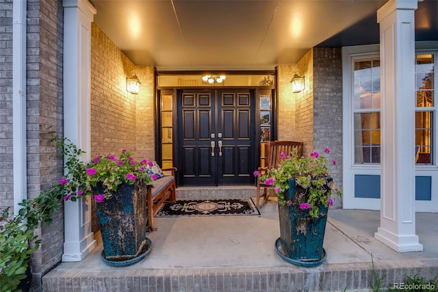 doorway to property featuring a porch and brick siding