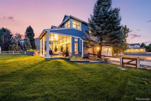 back of property at dusk featuring a garage, a patio, a lawn, and fence