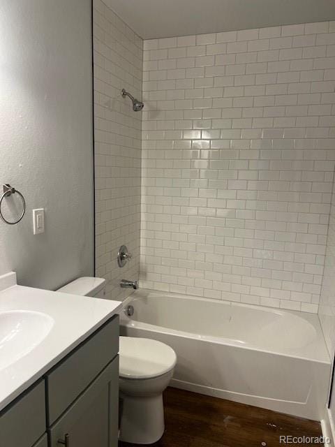 bathroom with washtub / shower combination, toilet, wood finished floors, and vanity