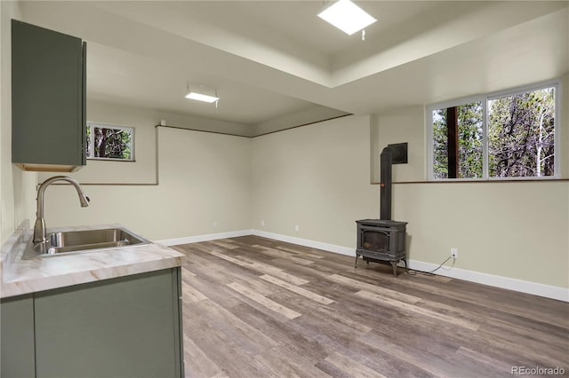 586 Alpine Way, Idaho Springs, CO 80452 - interior space featuring light wood finished floors, a wood stove, light countertops, a tray ceiling, and gray cabinets