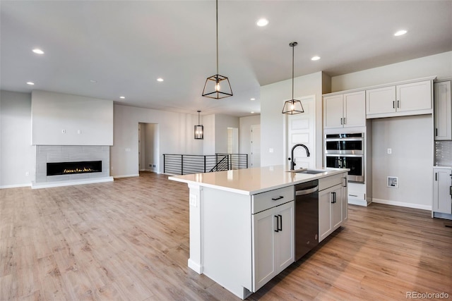 kitchen featuring white cabinetry, stainless steel appliances, an island with sink, and hanging light fixtures