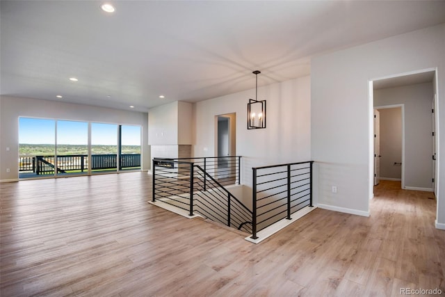 empty room featuring an inviting chandelier and light wood-type flooring