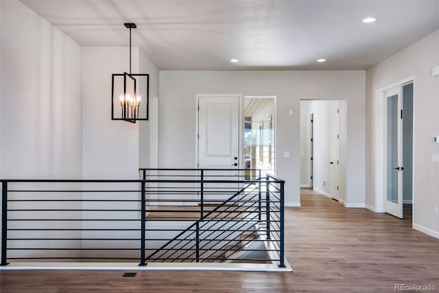 hall with wood-type flooring and an inviting chandelier