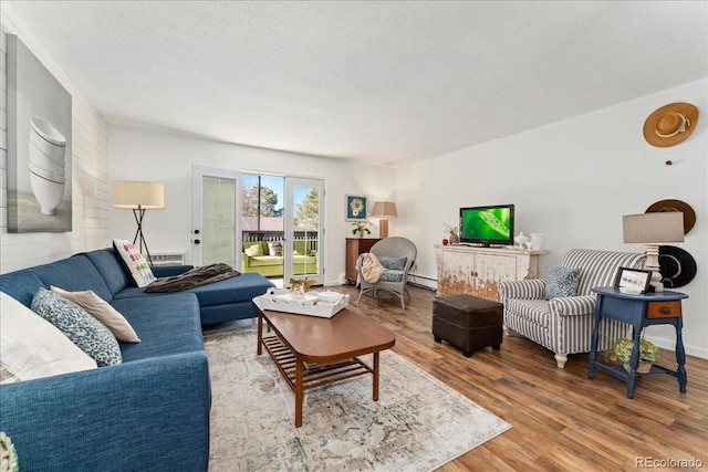 living room featuring a textured ceiling, baseboard heating, and wood finished floors