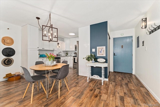 dining room with dark wood-type flooring, a notable chandelier, and baseboards