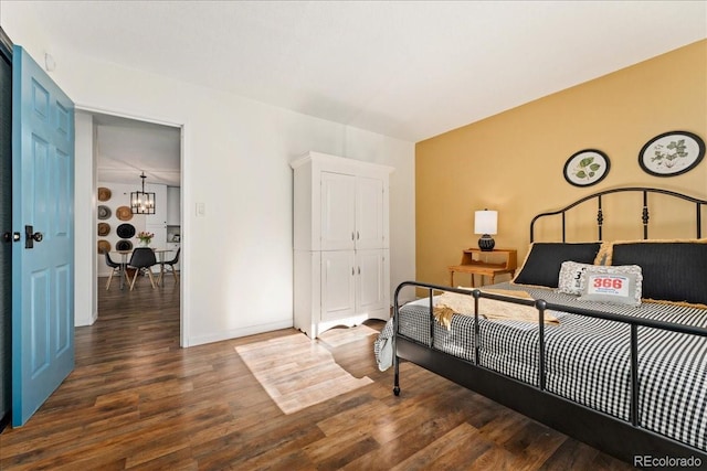 bedroom featuring a closet, baseboards, an inviting chandelier, and wood finished floors