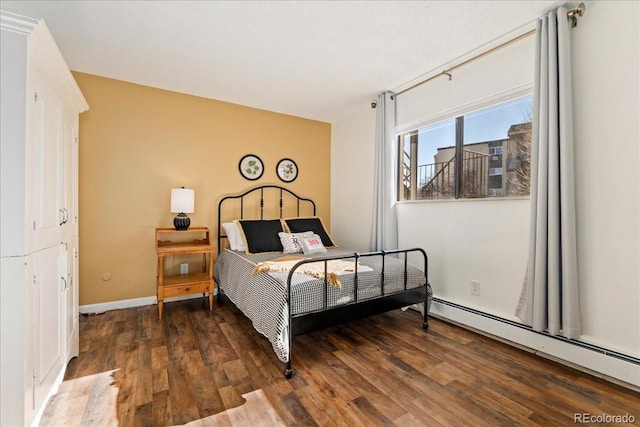 bedroom with baseboard heating, baseboards, and wood finished floors