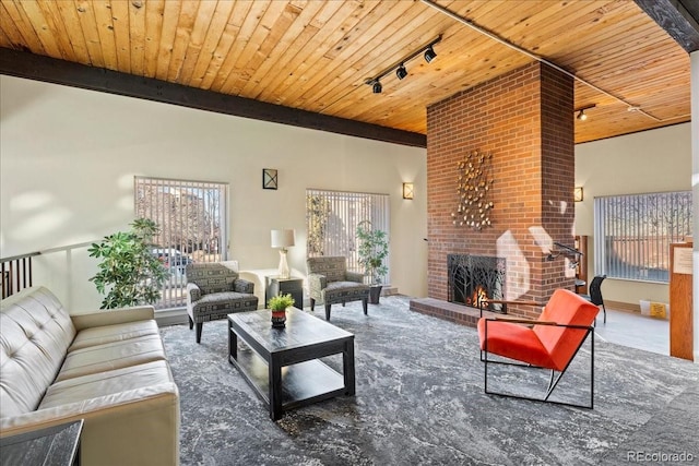 living area featuring beam ceiling, a brick fireplace, rail lighting, and wood ceiling