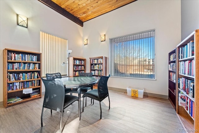 dining area with wood finished floors, baseboards, beam ceiling, a towering ceiling, and wooden ceiling