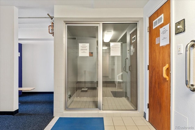 bathroom featuring tile patterned flooring, visible vents, a shower stall, and baseboards