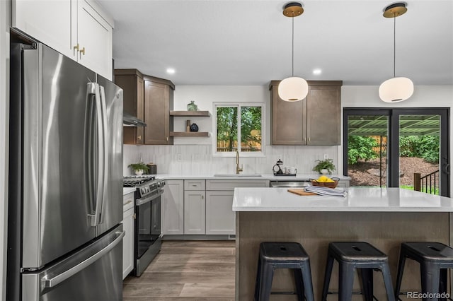 10067 W 68th Pl, Arvada, CO 80004 - kitchen featuring stainless steel appliances, open shelves, light countertops, a kitchen breakfast bar, and decorative backsplash