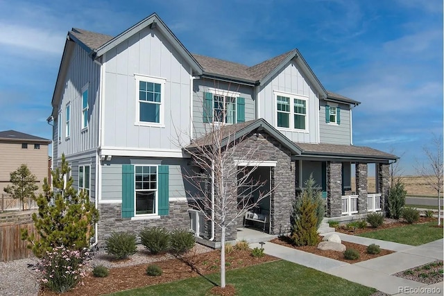 view of front of property with stone siding, a porch, board and batten siding, and a front yard