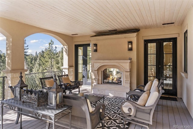 wooden terrace with french doors and a warm lit fireplace