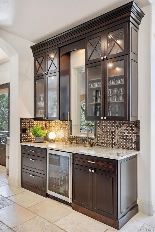 bar with tasteful backsplash, arched walkways, beverage cooler, and indoor wet bar