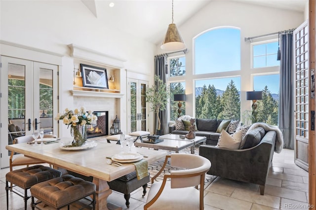 dining area featuring french doors, high vaulted ceiling, and a glass covered fireplace
