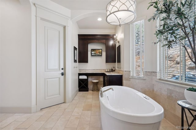 full bath featuring tile patterned flooring, tile walls, and a soaking tub