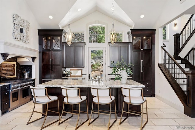 kitchen with a kitchen bar, high vaulted ceiling, range with two ovens, and light stone countertops