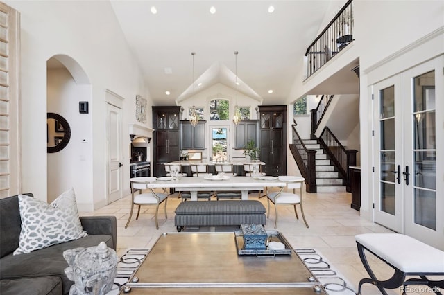 living room with high vaulted ceiling, arched walkways, stairway, and french doors