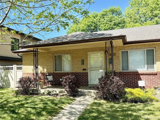 doorway to property featuring brick siding, roof with shingles, and a porch