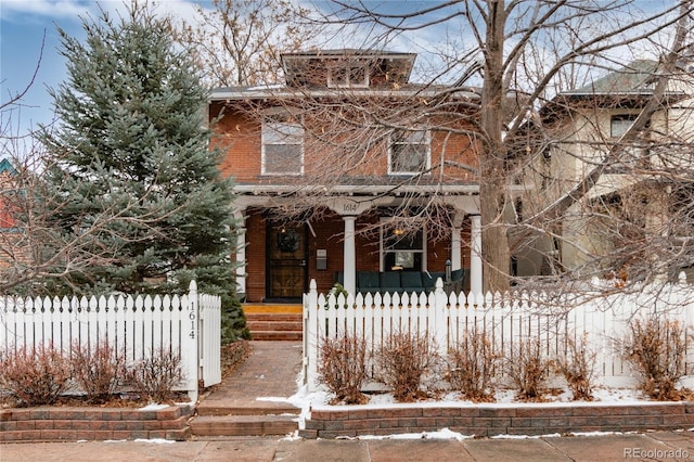 american foursquare style home with covered porch and a fenced front yard