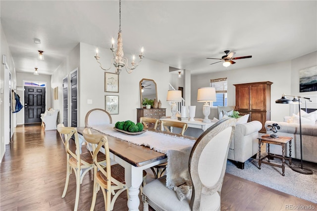 dining space with ceiling fan with notable chandelier and dark hardwood / wood-style flooring