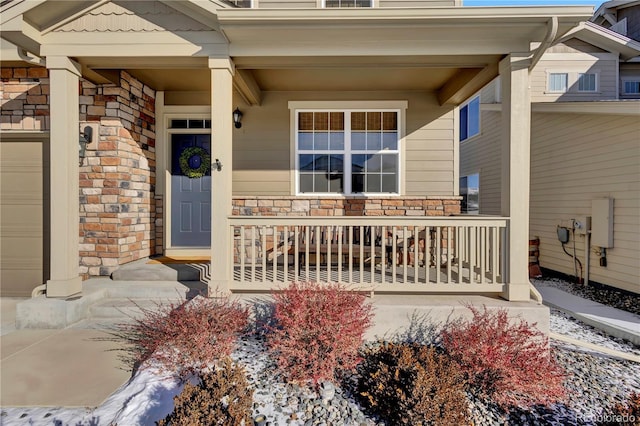 view of exterior entry with stone siding, covered porch, and an attached garage