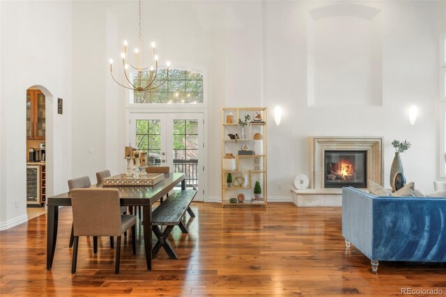 155 S Poplar St, Denver, CO 80230 - dining area featuring a towering ceiling, arched walkways, a chandelier, hardwood / wood-style floors, and a fireplace