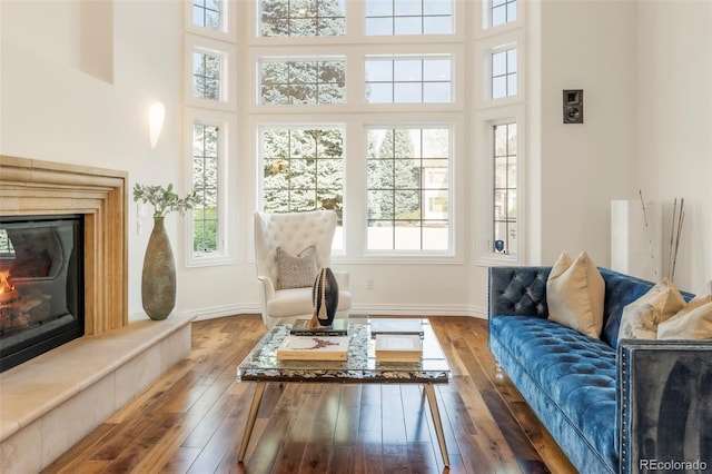 155 S Poplar St, Denver, CO 80230 - living room featuring a glass covered fireplace, wood-type flooring, a towering ceiling, and baseboards