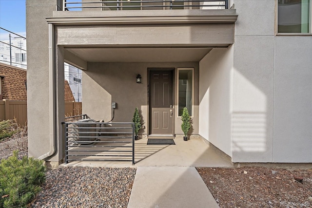 view of exterior entry featuring a patio area and a balcony