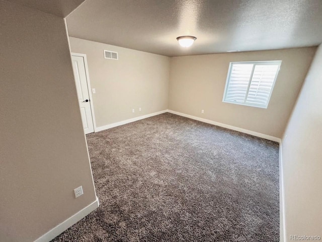 carpeted empty room featuring baseboards, visible vents, and a textured ceiling