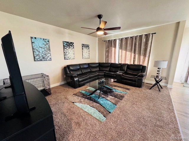 living room with a ceiling fan and baseboards