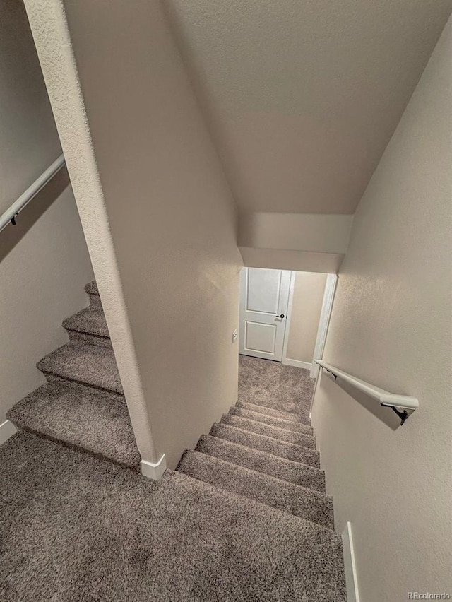 staircase with lofted ceiling, carpet, a textured wall, and a textured ceiling