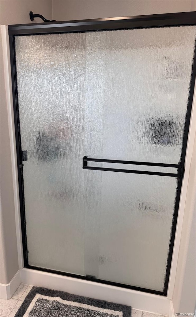 bathroom with tile patterned flooring, a stall shower, and baseboards