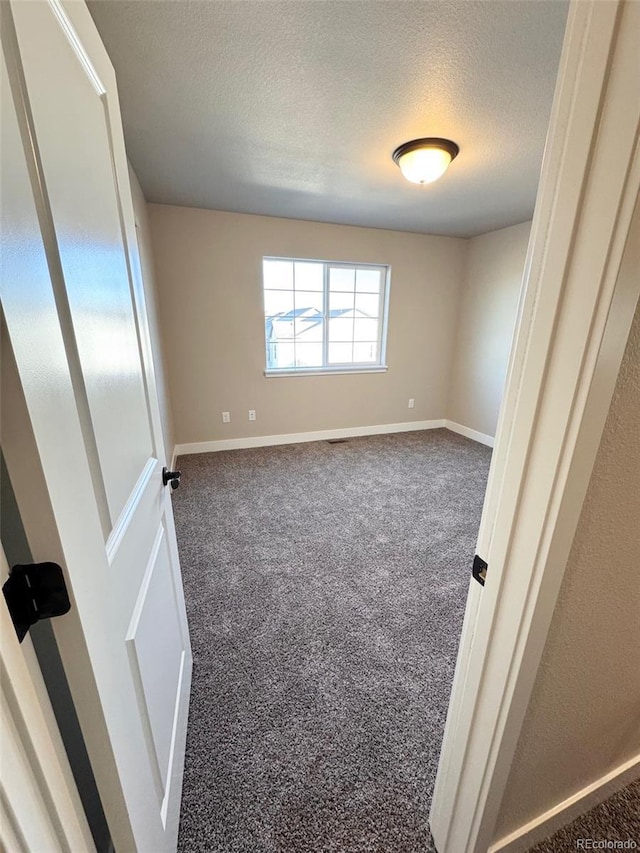 carpeted empty room featuring baseboards and a textured ceiling