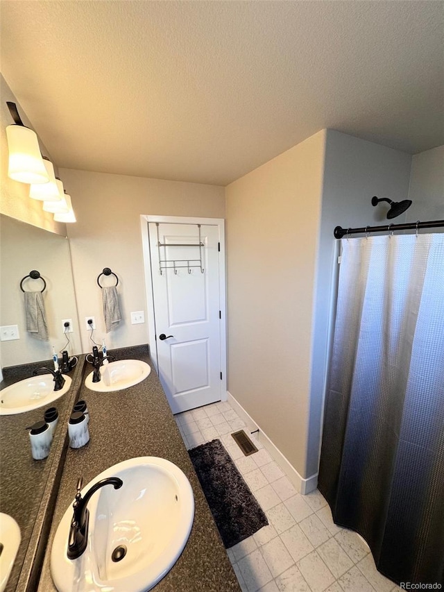 bathroom with a sink, a textured ceiling, and double vanity