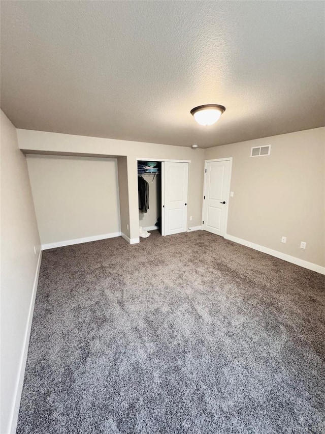 unfurnished bedroom with visible vents, baseboards, a textured ceiling, and carpet floors