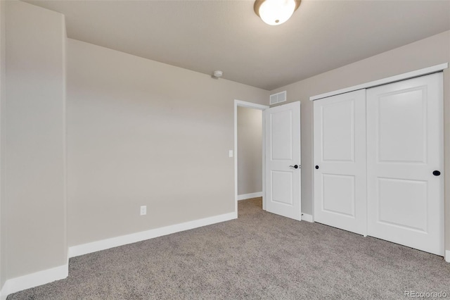 unfurnished bedroom with baseboards, visible vents, carpet, and a closet