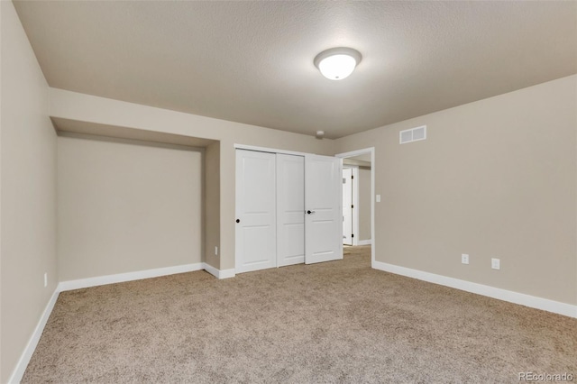 unfurnished bedroom featuring carpet flooring, baseboards, visible vents, and a closet