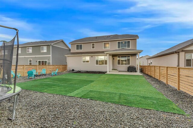 back of house featuring a fenced backyard, a trampoline, a patio area, and a yard
