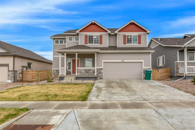 craftsman-style house with covered porch, driveway, a front yard, a garage, and stone siding